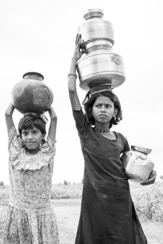 Children and Water - Girls carrying multiple water pots from a distant handpump in a village in Shivpuri district, Madhya Pradesh